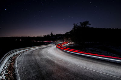 Light trails on road against sky at night