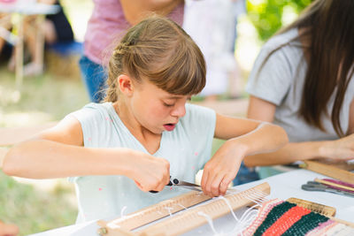 Girl weaving small rug with pattern at masterclass on weaving.