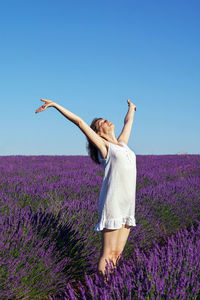 Woman with arms raised on field against clear sky