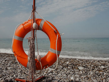 Clothes hanging on rope at beach against sky