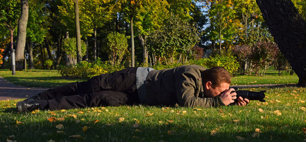 Man photographing through digital camera on grassy field