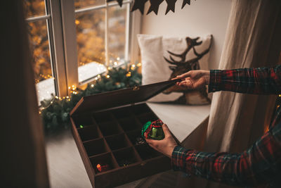 Cropped image of keeping christmas decoration in wooden box at home
