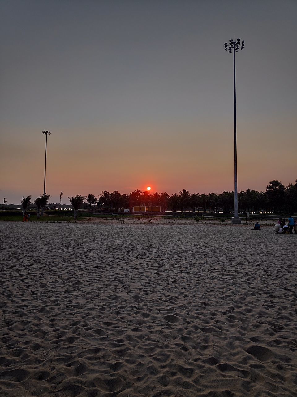 STREET LIGHTS ON BEACH AGAINST SKY AT SUNSET