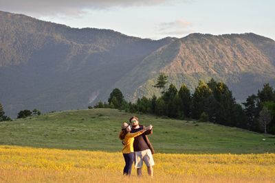 Full length of young woman and man standing on mountain road