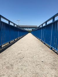 Empty footbridge against clear blue sky