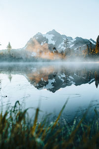 Scenic view of lake by snowcapped mountains against sky