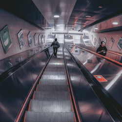 Rear view of man walking on escalator