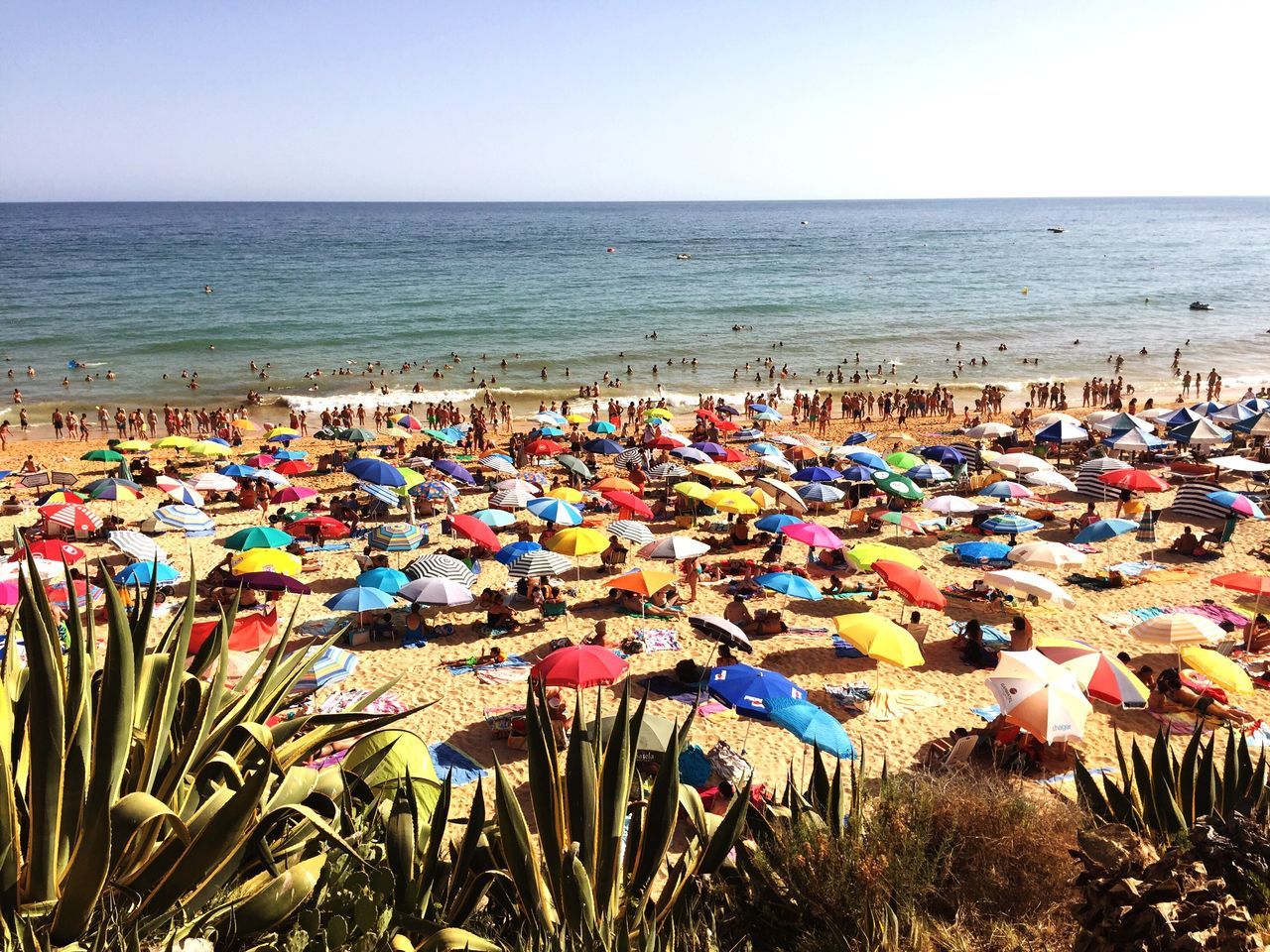 sea, beach, horizon over water, water, shore, beach umbrella, tranquility, tranquil scene, nature, beauty in nature, large group of objects, scenics, vacations, sky, summer, blue, abundance, parasol, outdoors, day, idyllic, multi colored, absence, ocean, group of objects, coastline, arrangement