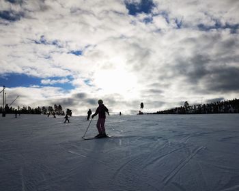 People on snowy field against sky during winter