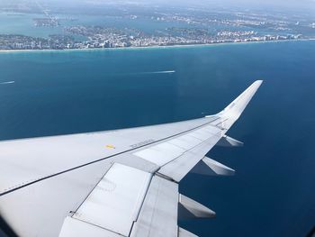 Airplane flying over sea against cityscape