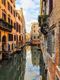 Canal amidst buildings in city against sky