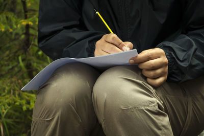 Midsection of man reading book while sitting on seat
