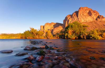 Rocks in the salt river with sunset light on the mountains in the distance