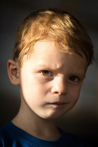 Close-up portrait of boy making face against gray background