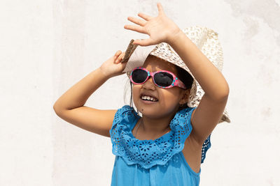 An indian girl wearing sunglasses and holding hat looking at the sun in summer on white background