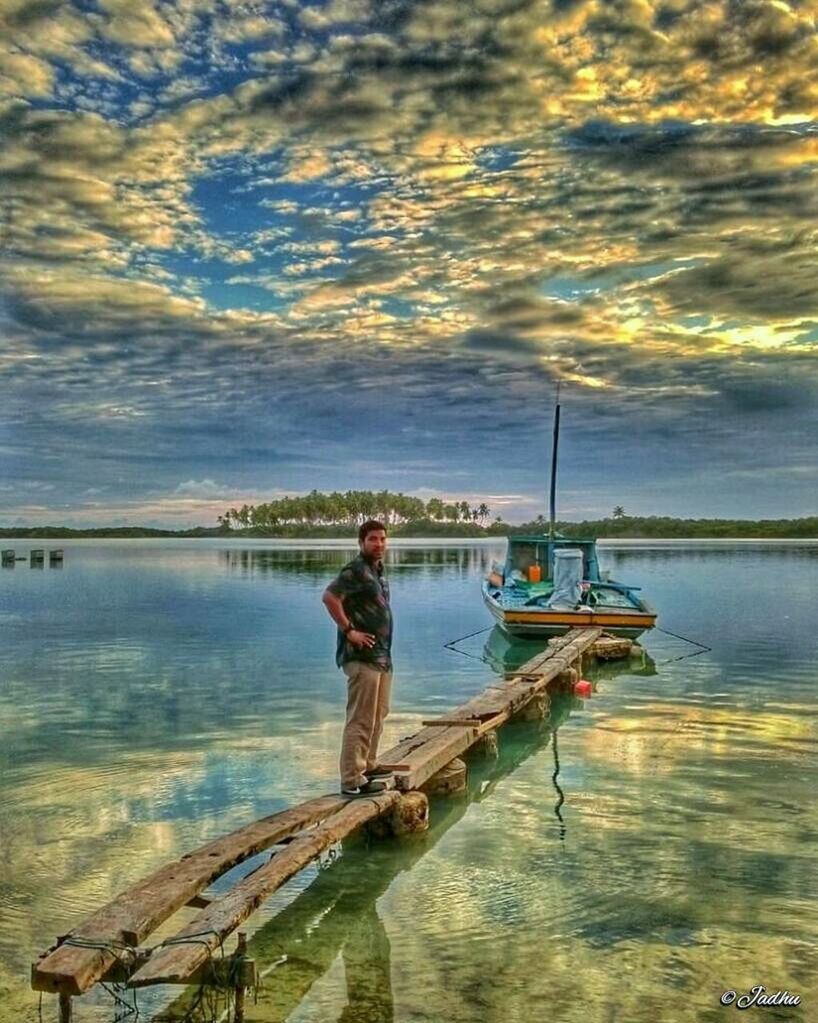 water, lifestyles, leisure activity, sky, cloud - sky, sea, nautical vessel, cloudy, full length, tranquility, beauty in nature, scenics, vacations, nature, standing, rear view, tranquil scene, boat