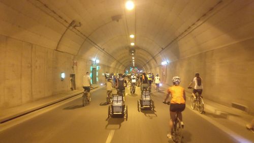 Rear view of people walking in illuminated tunnel