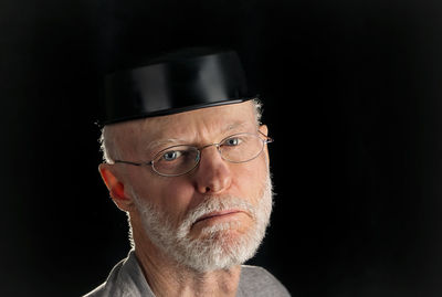 Portrait of man wearing eyeglasses against black background