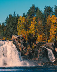 Scenic view of waterfall in forest against sky during autumn