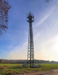 Low angle view of communications tower on field against sky