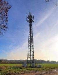 Low angle view of communications tower on field against sky