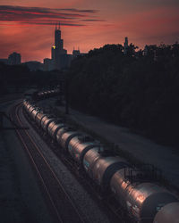 High angle view of railroad tracks by buildings against sky during sunset