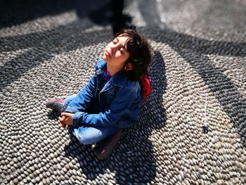 High angle view of girl sitting on footpath