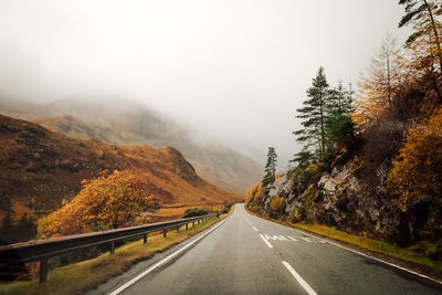 Road amidst trees against sky