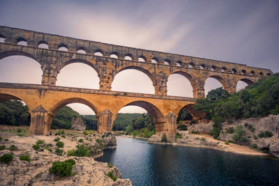 Low angle view of arch bridge over river against sky