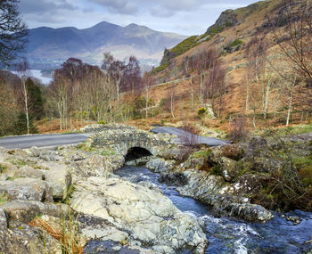 River flowing by mountain against sky