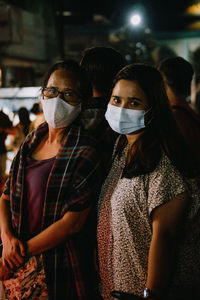 Portrait of mother and daughter wearing mask standing outdoors