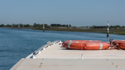 Boat on riverbank against clear blue sky