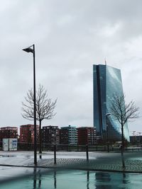 Modern buildings by river against sky in city