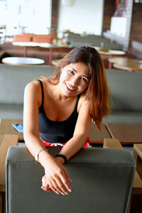 Portrait of smiling young woman sitting on chair