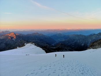 People on snowcapped mountains against sky during winter