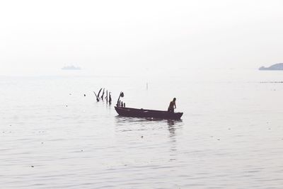 Men in boat on sea against sky