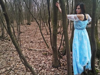 Young woman standing by bare tree