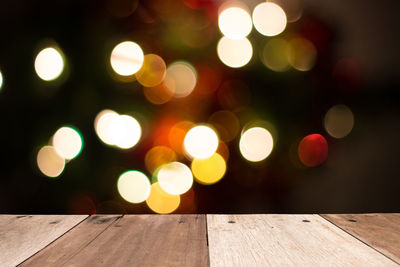 Close-up of empty wooden table against defocused lights