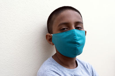 Portrait of boy wearing mask against white wall