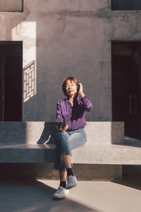 Full length portrait of woman standing against built structure