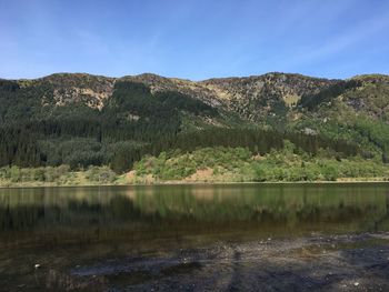 Scenic view of lake by mountains against sky