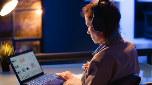 Side view of woman using laptop at home