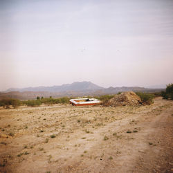 Abandoned boat on land against sky