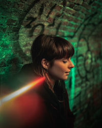 Portrait of a young woman looking away against wall