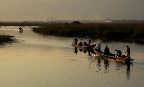 Idyllic view of people in boats of on lake at sunset