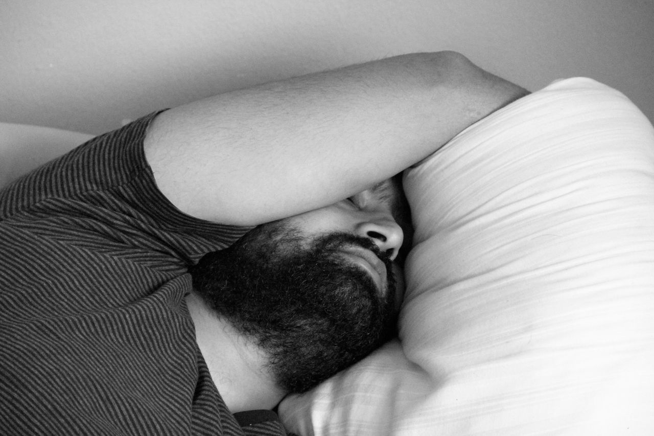 furniture, relaxation, lying down, indoors, one person, sleeping, resting, bed, real people, adult, portrait, eyes closed, men, headshot, high angle view, pillow, beard, lifestyles, leisure activity, obscured face