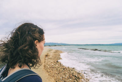 Girl looking at the sea on a cloudy and sad day with the rough sea