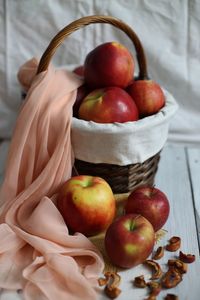 Close-up of apples and scarf in basket on table
