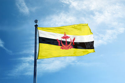 Low angle view of brunei flag against blue sky