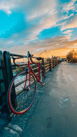 Bicycle parked by railing in city against sky